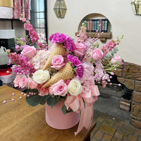 Pink and white rose arrangement in a pink hatbox with waffle cones