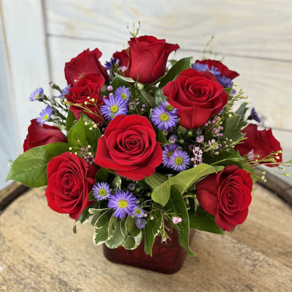Red roses and purple daisies in a red vase