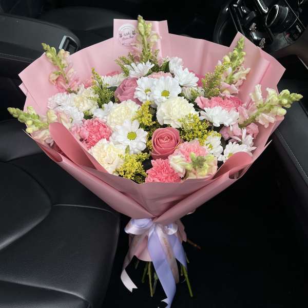Pink bouquet with roses, daisies, carnations, and snapdragons wrapped in pink paper