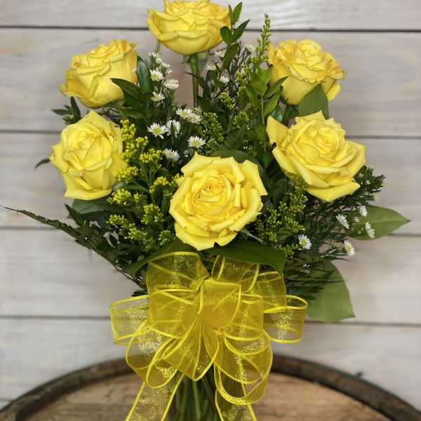 Bouquet of yellow roses in a glass vase with a yellow ribbon