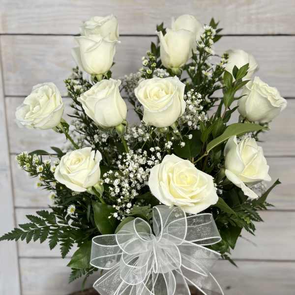 White roses in a clear glass vase with a sheer white bow