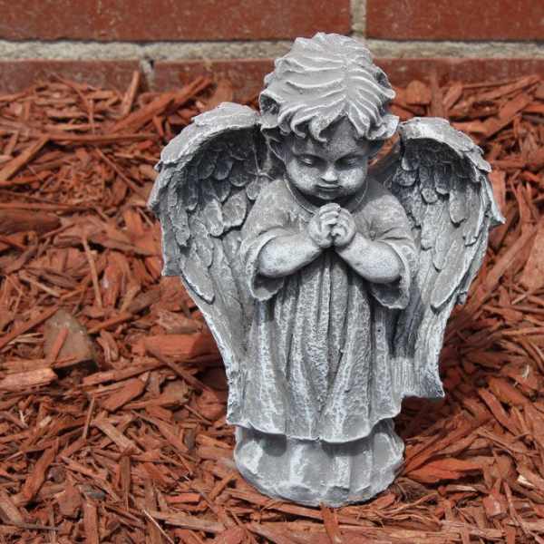 Gray angel garden statue with folded hands on red mulch