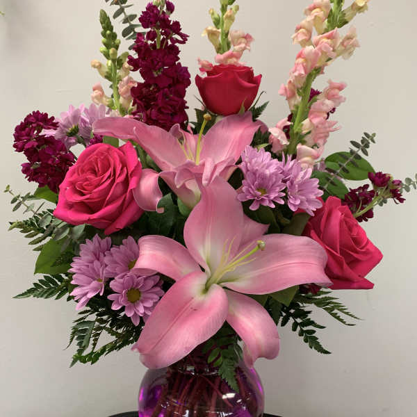 Pink lilies and roses in a purple glass vase