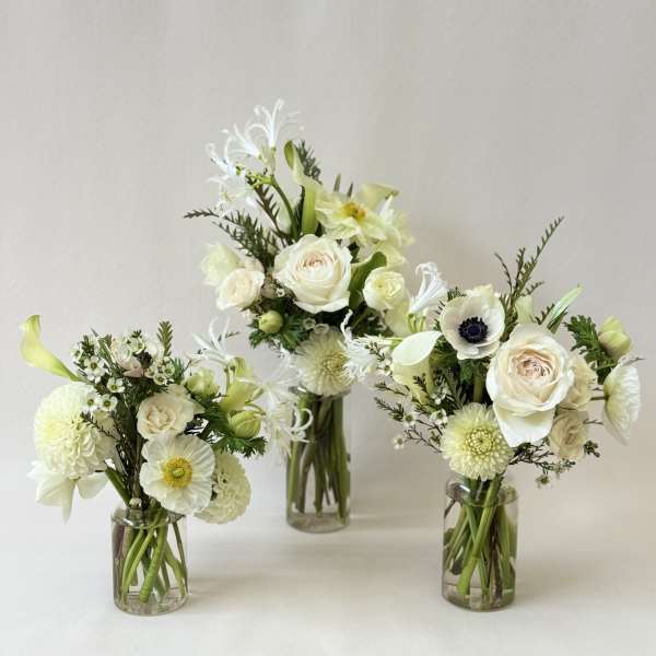 Three white floral arrangements in clear glass vases