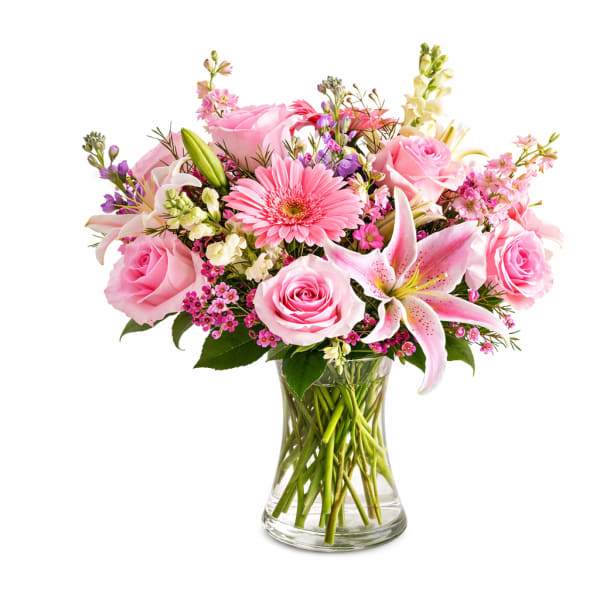 Pink roses and lilies arranged in a clear glass vase