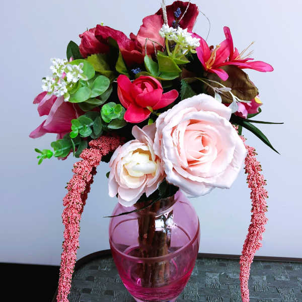 Pink and red floral arrangement in a pink glass vase