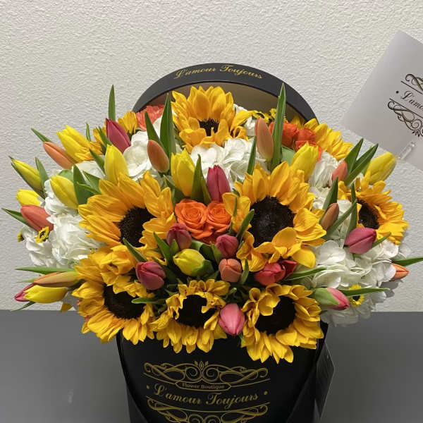 Bouquet of sunflowers, tulips, and white hydrangeas in a black hat box