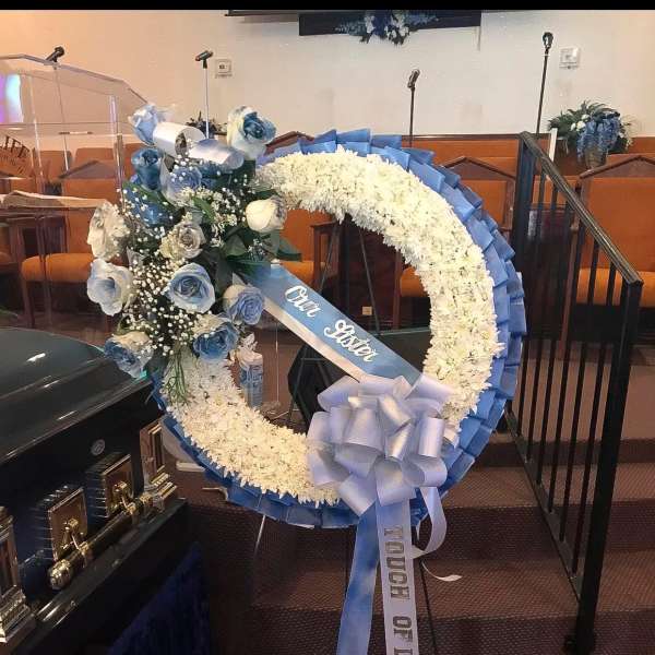Blue and white funeral wreath with roses and a ribbon on an easel