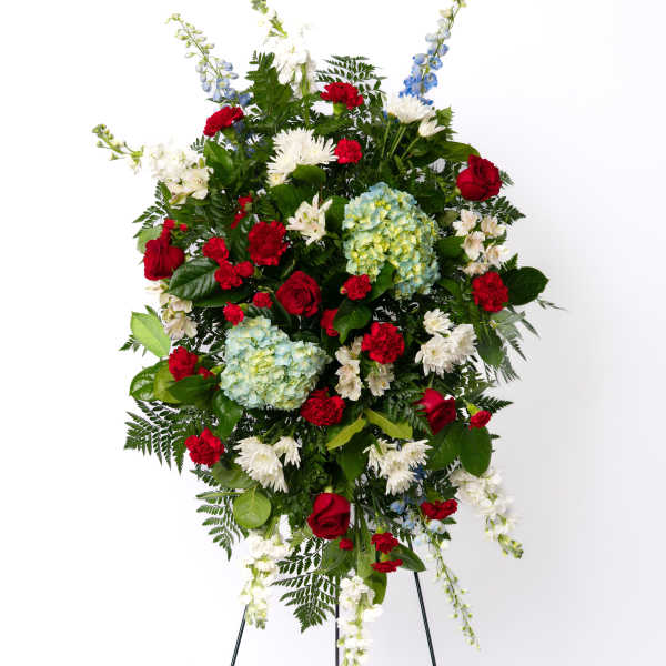 Tall red, white, and blue standing spray with roses, hydrangeas, and mums on a metal easel