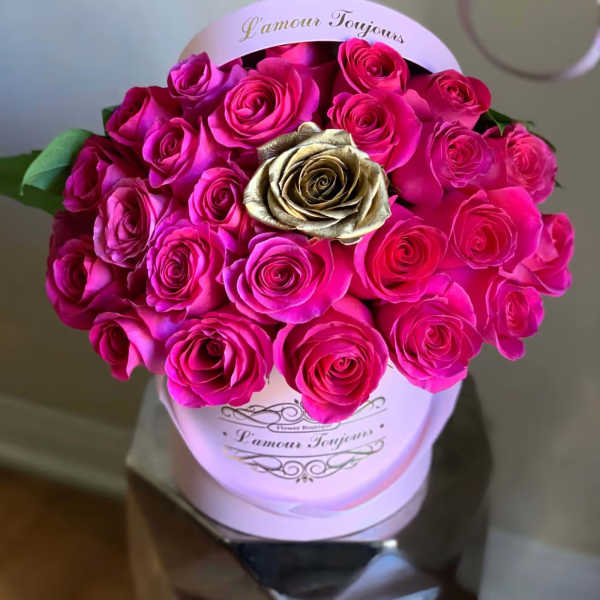 Bouquet of bright pink roses in a round hat box with one gold rose