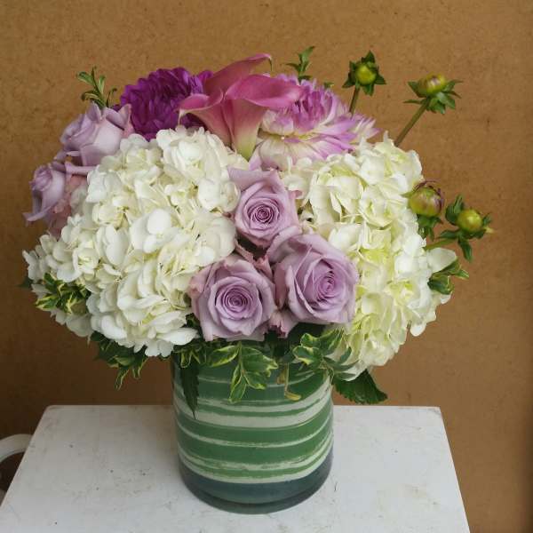 Lavender roses and white hydrangeas in a striped green vase