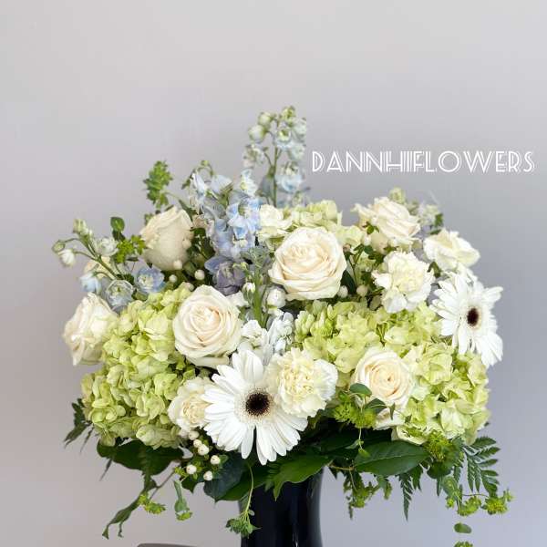 White roses and green hydrangeas in a dark blue vase