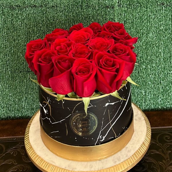 Round box filled with red roses on a gold base