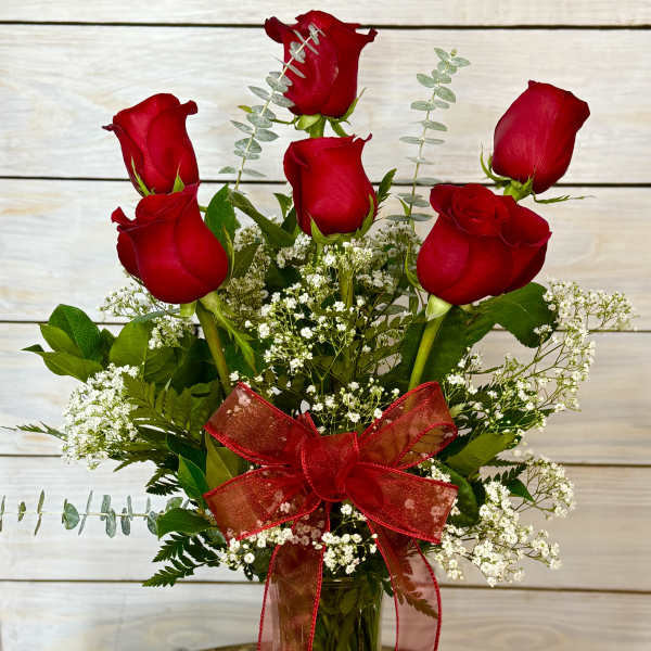Bouquet of red roses with baby's breath in a glass vase and red ribbon