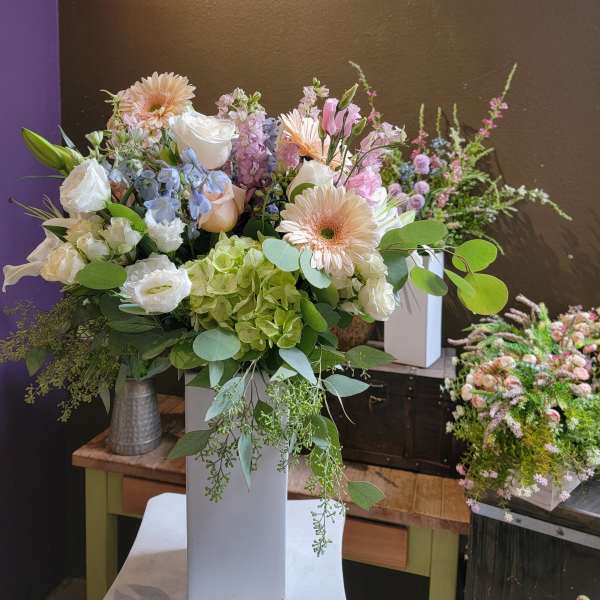 Mixed pastel bouquet in a tall white vase with gerberas, roses, and hydrangeas