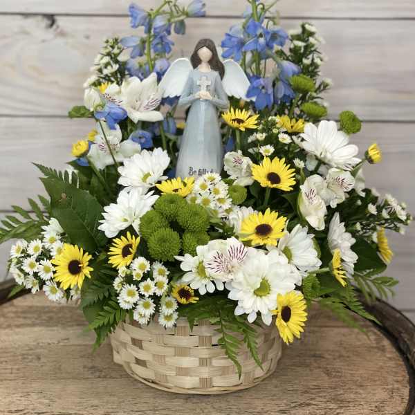 Basket arrangement with white and yellow flowers and a small angel figurine