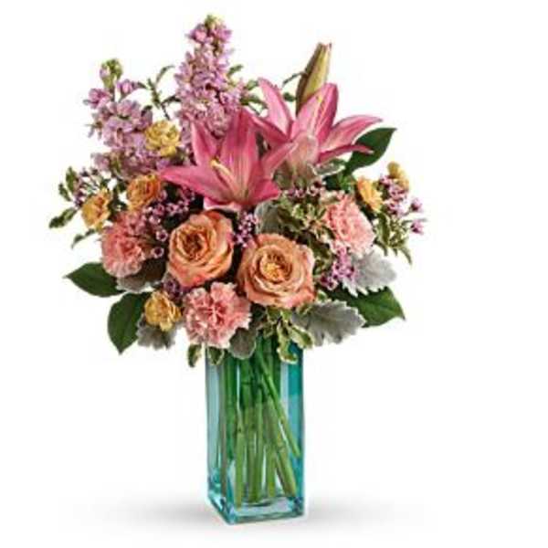 Pink and peach floral arrangement in a blue glass vase