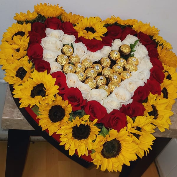 Heart-shaped arrangement of red and white roses with sunflowers and gold chocolates