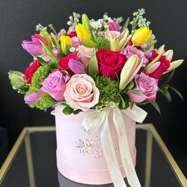 Mixed bouquet of roses and tulips in a pink hatbox