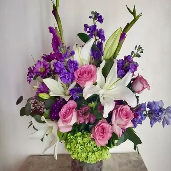 Bouquet of pink roses, white lilies, and purple flowers in a vase