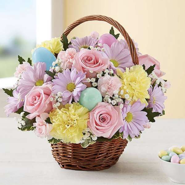 Basket of pastel flowers with decorative eggs