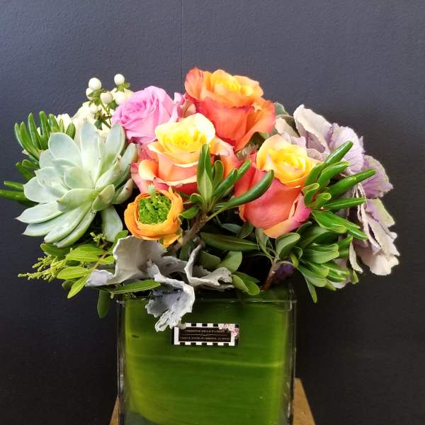 Mixed bouquet of roses and succulents in a square glass vase
