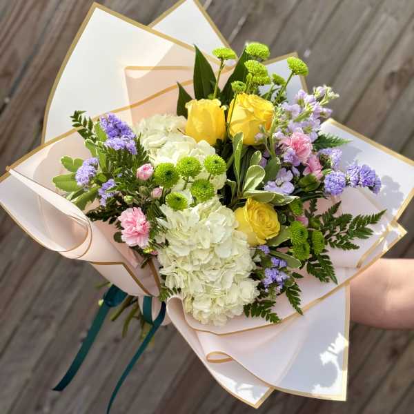 Hand-tied bouquet of yellow roses, white hydrangea, and purple flowers