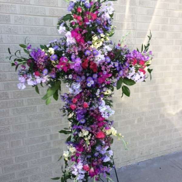Tall floral cross arrangement in pink, purple, and white flowers