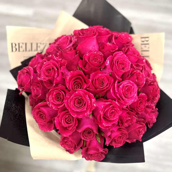 Bouquet of bright pink roses wrapped in black and cream paper