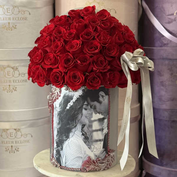Red rose arrangement in a decorated cylindrical box with a ribbon bow