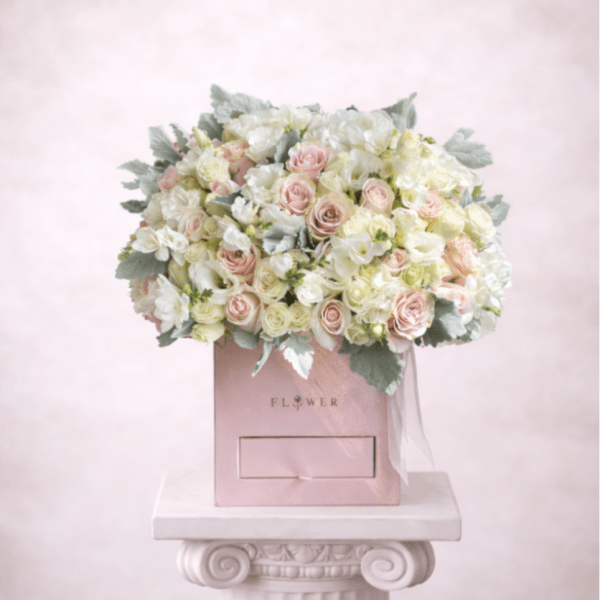 Pink and white rose bouquet in a pink box on a pedestal