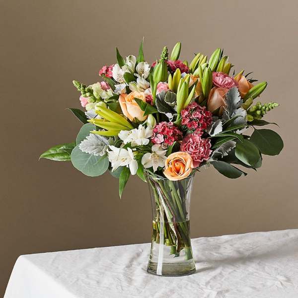 Mixed bouquet of lilies, roses, carnations, and alstroemeria in a glass vase