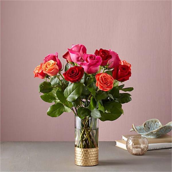 Bouquet of red, pink, and orange roses in a clear glass vase