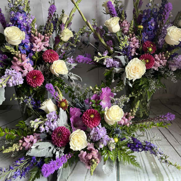 Large floral arrangement with cream roses, purple blooms, and pink flowers