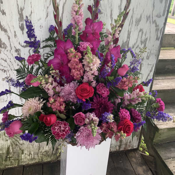 Tall pink and purple floral arrangement in a white vase