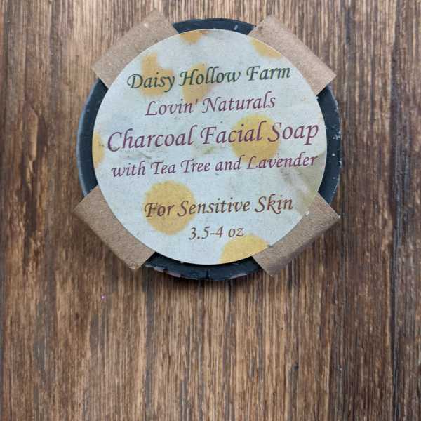 Round charcoal facial soap bar with a labeled paper top