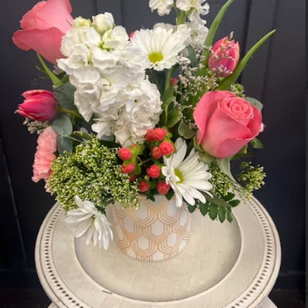 Pink roses and white flowers arranged in a patterned vase