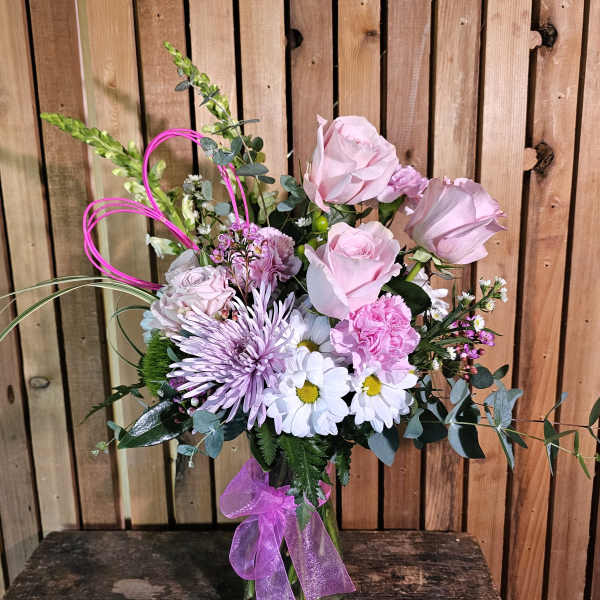 Pink and lavender bouquet in a glass vase with a purple ribbon