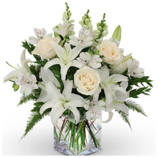 White lilies and cream roses in a clear square vase