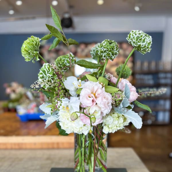 Mixed floral arrangement in a clear glass vase with green and white blooms