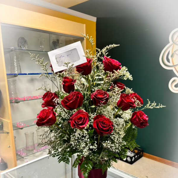 Red roses arranged in a vase with baby's breath and greenery