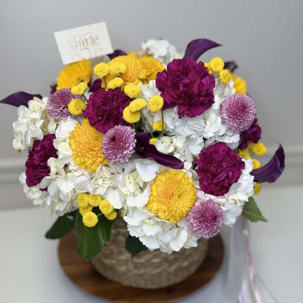 Mixed bouquet of white, yellow, magenta, and lavender flowers in a basket