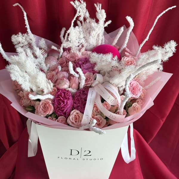Pink roses and peonies in a white gift box with white decorative branches