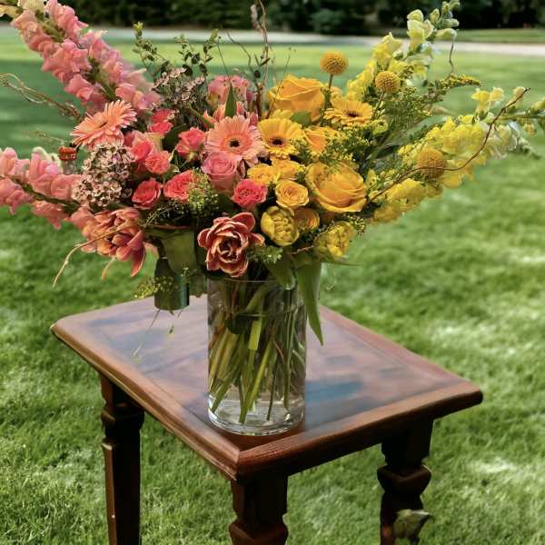 Colorful mixed bouquet in a clear glass vase on a wooden table