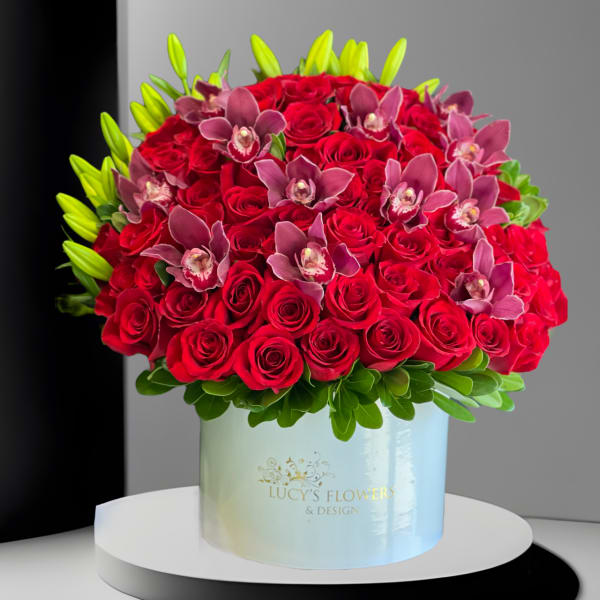 Red rose arrangement with pink orchids in a pale blue box