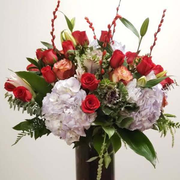 Red roses and pale hydrangeas arranged in a dark vase