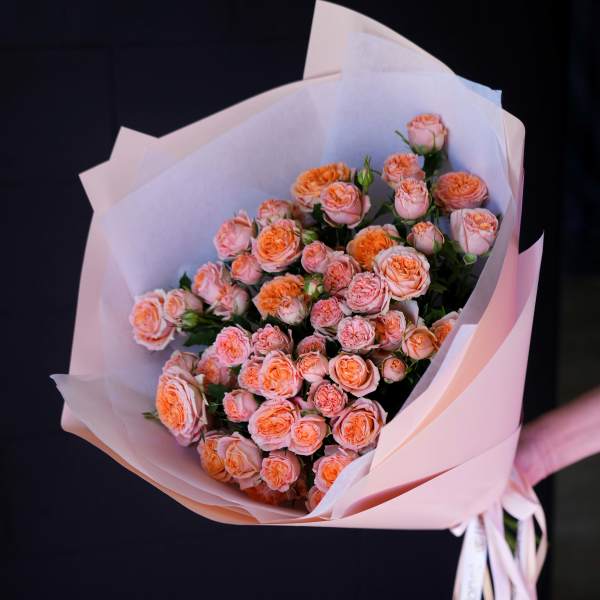 Bouquet of peach spray roses wrapped in pale pink paper