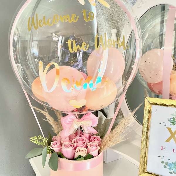 Pink roses in a round box with a clear balloon above