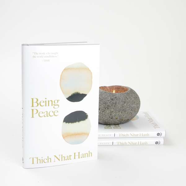 Book with a lit stone candle beside two stacked copies