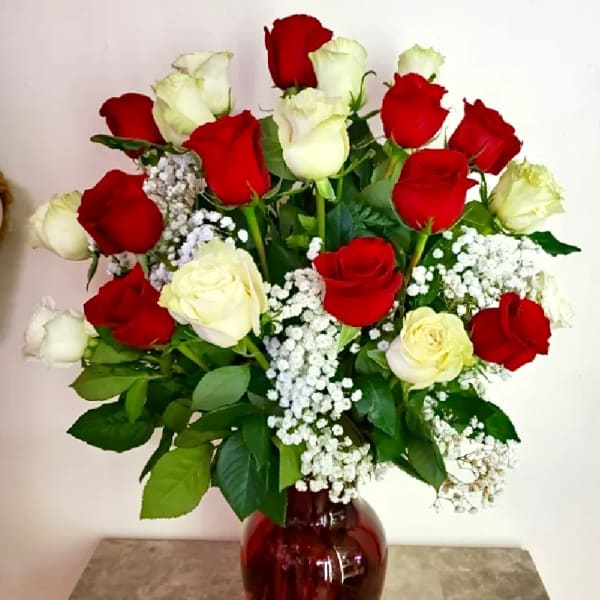 Red and white roses in a red glass vase